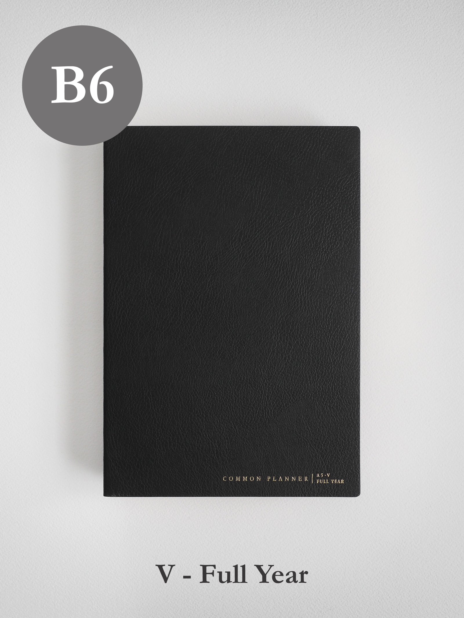 Minimalist black B6 planner cover with a smooth, faux leather finish, featuring subtle branding for the "Common Planner | As-V Full Year" theme.
