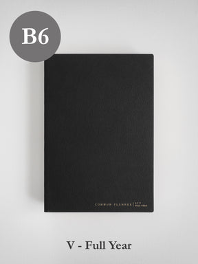 Minimalist black B6 planner cover with a smooth, faux leather finish, featuring subtle branding for the "Common Planner | As-V Full Year" theme.
