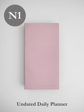 Minimalist undated daily planner cover in soft blush pink, featuring a clean design and subtle branding detail for an elegant aesthetic.