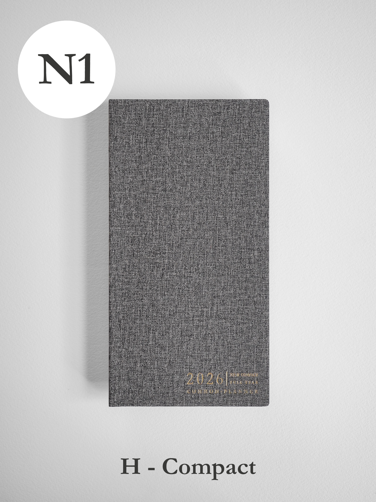 Textured charcoal gray compact planner cover, designed for 2026, featuring a subtle embossed logo and title for a full-year planning journal.