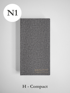 Textured charcoal gray compact planner cover, designed for 2026, featuring a subtle embossed logo and title for a full-year planning journal.