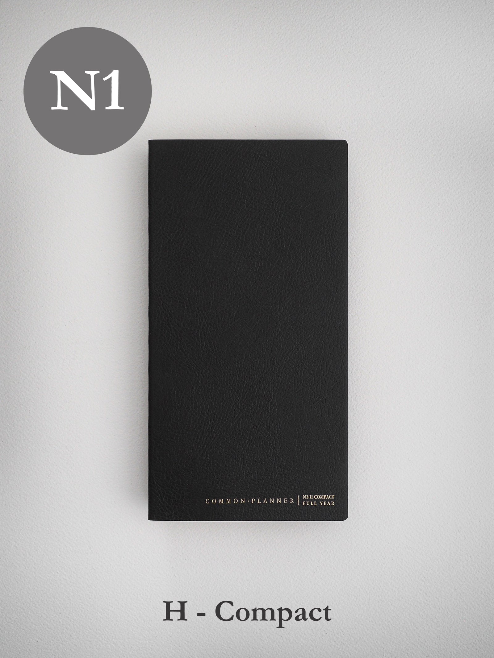 Sleek, black, undated planner journal with a textured cover, labeled "Common Planner N1 Compact Full Year," designed for organized scheduling.