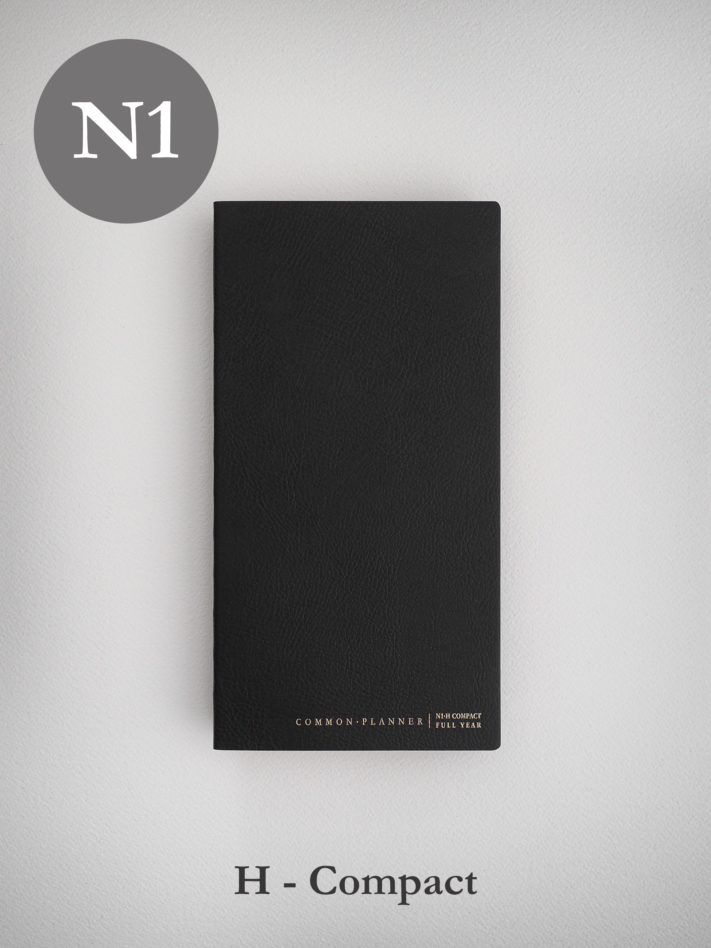Sleek, black, undated planner journal with a textured cover, labeled "Common Planner N1 Compact Full Year," designed for organized scheduling.