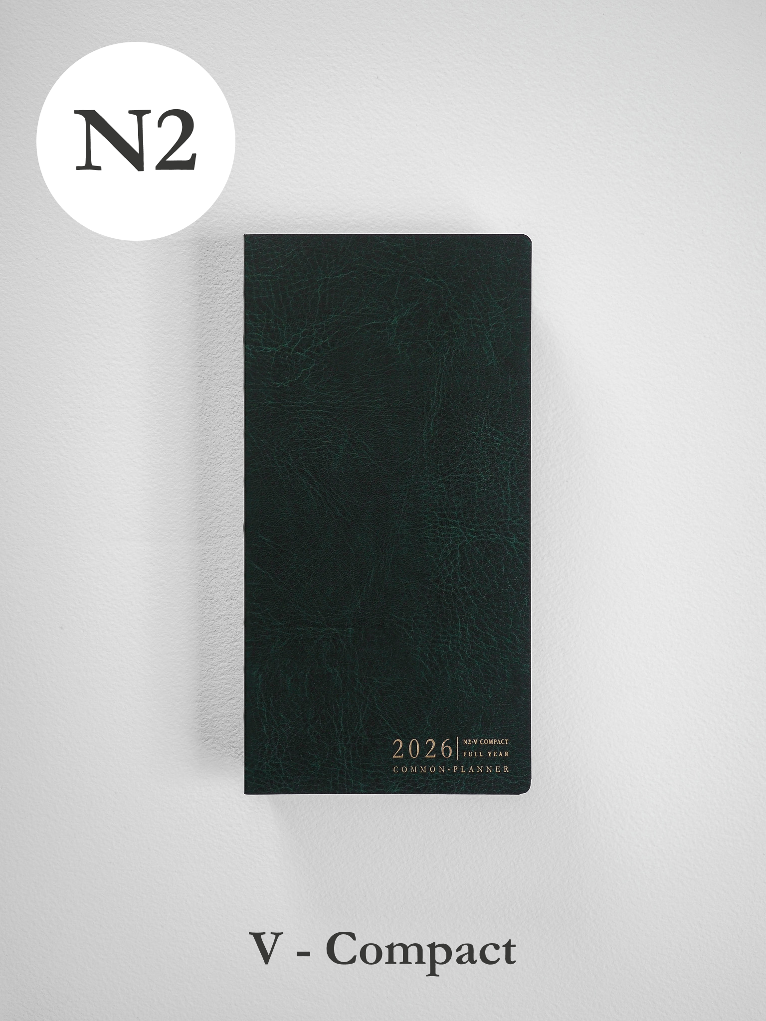 A deep slate green vertical planner featuring a subtly textured, faux-leather finish and elegant gold-foil embossing for the "2026 Common Planner."
