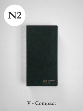 A deep slate green vertical planner featuring a subtly textured, faux-leather finish and elegant gold-foil embossing for the "2026 Common Planner."