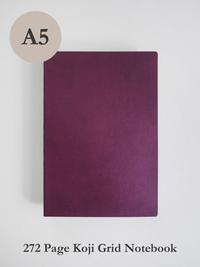 A dark purple A5 size Koji grid notebook shown flat against a light gray background, with a beige circle label reading 'A5' in the top left and text at the bottom reading '272 Page Koji Grid Notebook'.
#Color_Mulberry
