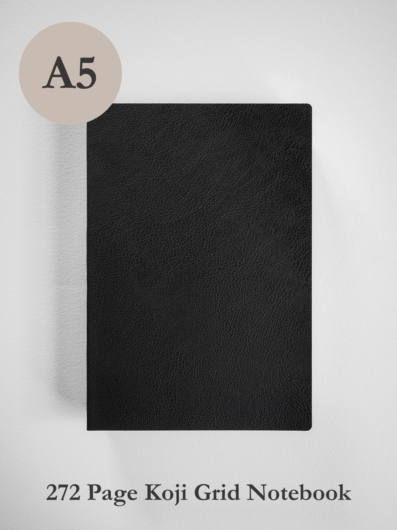 A black textured A5 size Koji grid notebook shown against a light gray background, with a beige circle label reading 'A5' in the top left and text at the bottom reading '272 Page Koji Grid Notebook'.
#Color_Onyx