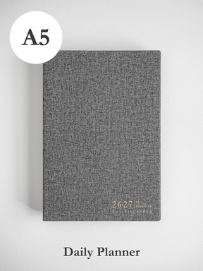 A sophisticated A5 academic daily planner featuring a heather gray, textured cover and subtle, centered printing for the 2026-2027 year.
