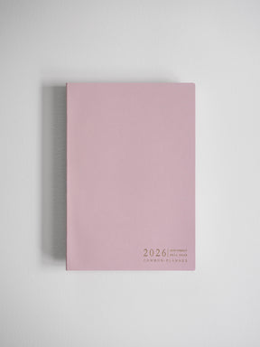 Minimalist A5 planner in solid blush pink featuring centered black text detailing "2026," "Full Year," and the "Common Planner" brand.