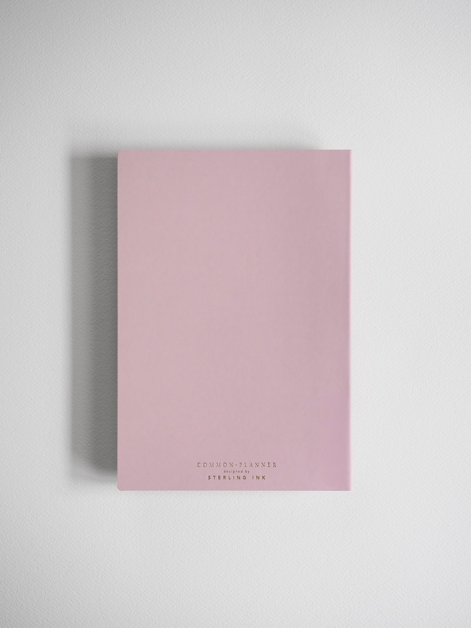 Pale pink A5 horizontal planner featuring the title "COMMON PLANNER" and "DESIGNED BY STERLING INK," perfect for yearly organization and journaling.