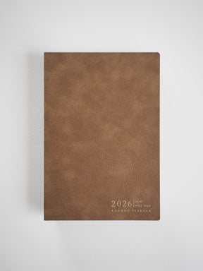 A textured, rich brown A5 planner cover for 2026, featuring the embossed "Common Planner" designation centered near the bottom edge.