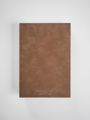 A solid, minimalist A5 planner cover in warm brown taupe, featuring elegant, embossed branding for Common Planner and Sterling Ink.
