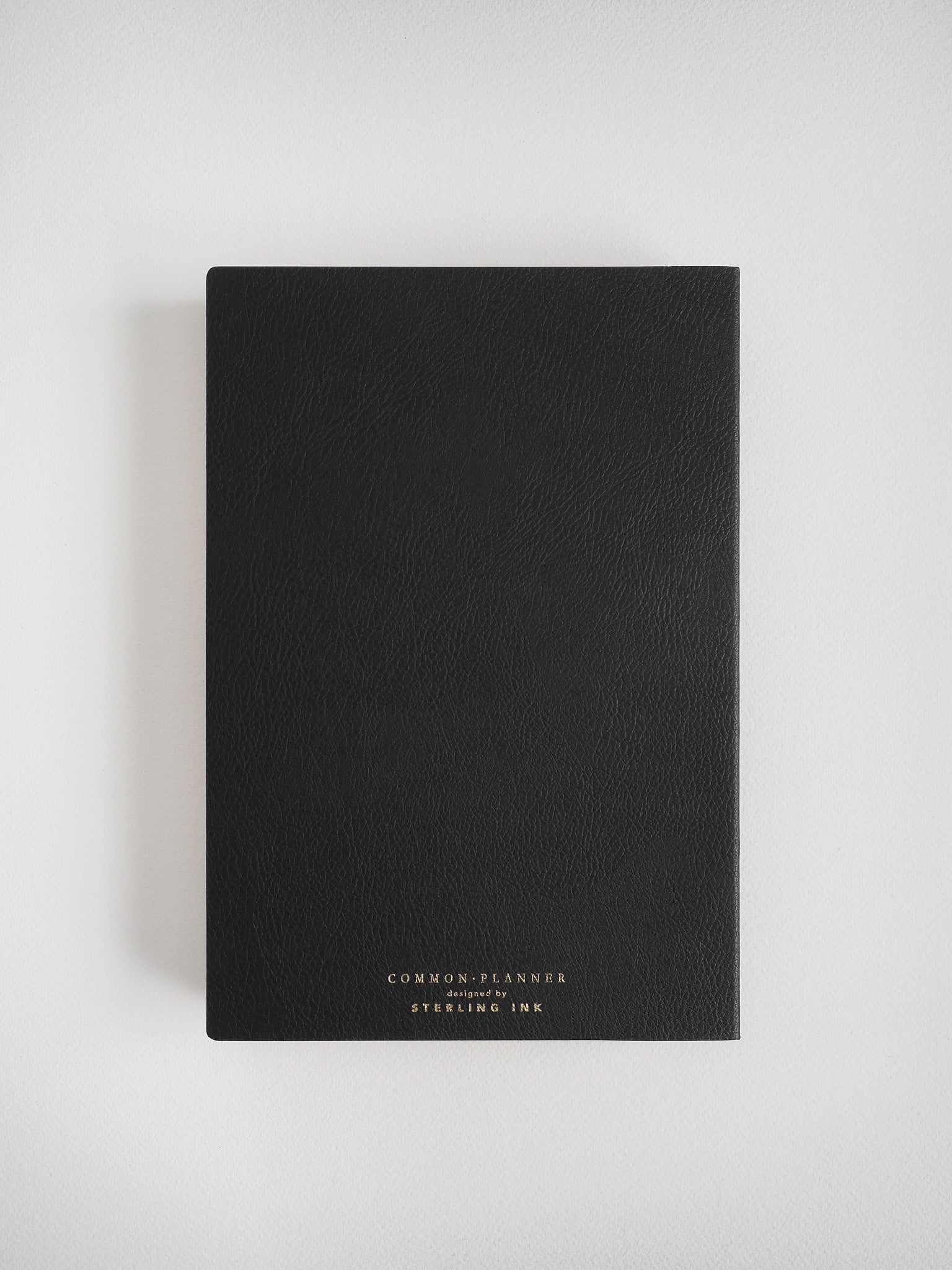 Elegant matte black A5 journal planner with a minimalist design, featuring silver or gold lettering and the branding "Common Planner" by "Sterling Ink."
