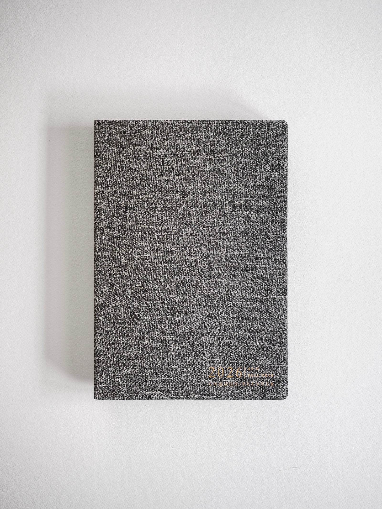 Textured dark gray A5 planner featuring elegant metallic gold foil lettering that displays "2026 Common Planner," ready for a full year of organization.