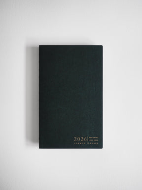 Sleek A5 vertical planner with a matte black cover, featuring minimal gold foil typography that reads "2026 Common Planner."