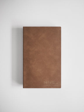 This elegant, warm brown A5 slim vertical planner features debossed gold lettering detailing the "2026 Common Planner" title.