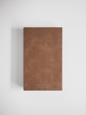 A slim, deep cocoa-brown planner featuring a minimalist design and embossed branding for 'COMMON PLANNER' and 'STEELING INK'.