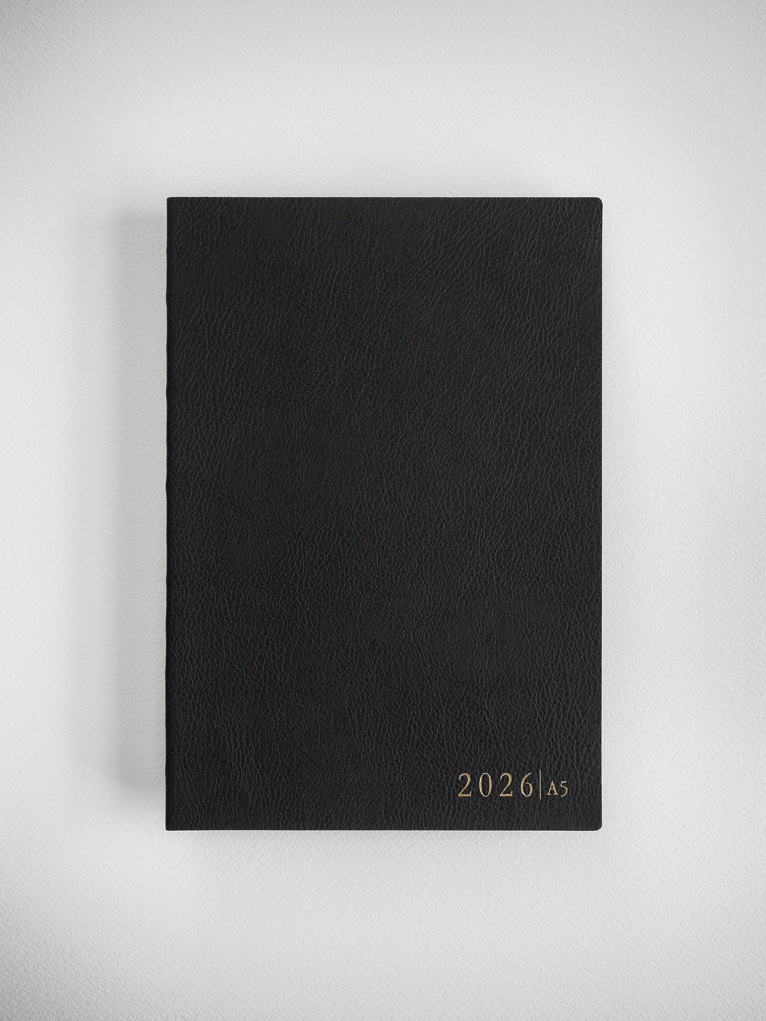 Minimalist black A5 planner cover for 2026, showcasing a sophisticated, matte finish with elegant, centered year typography.