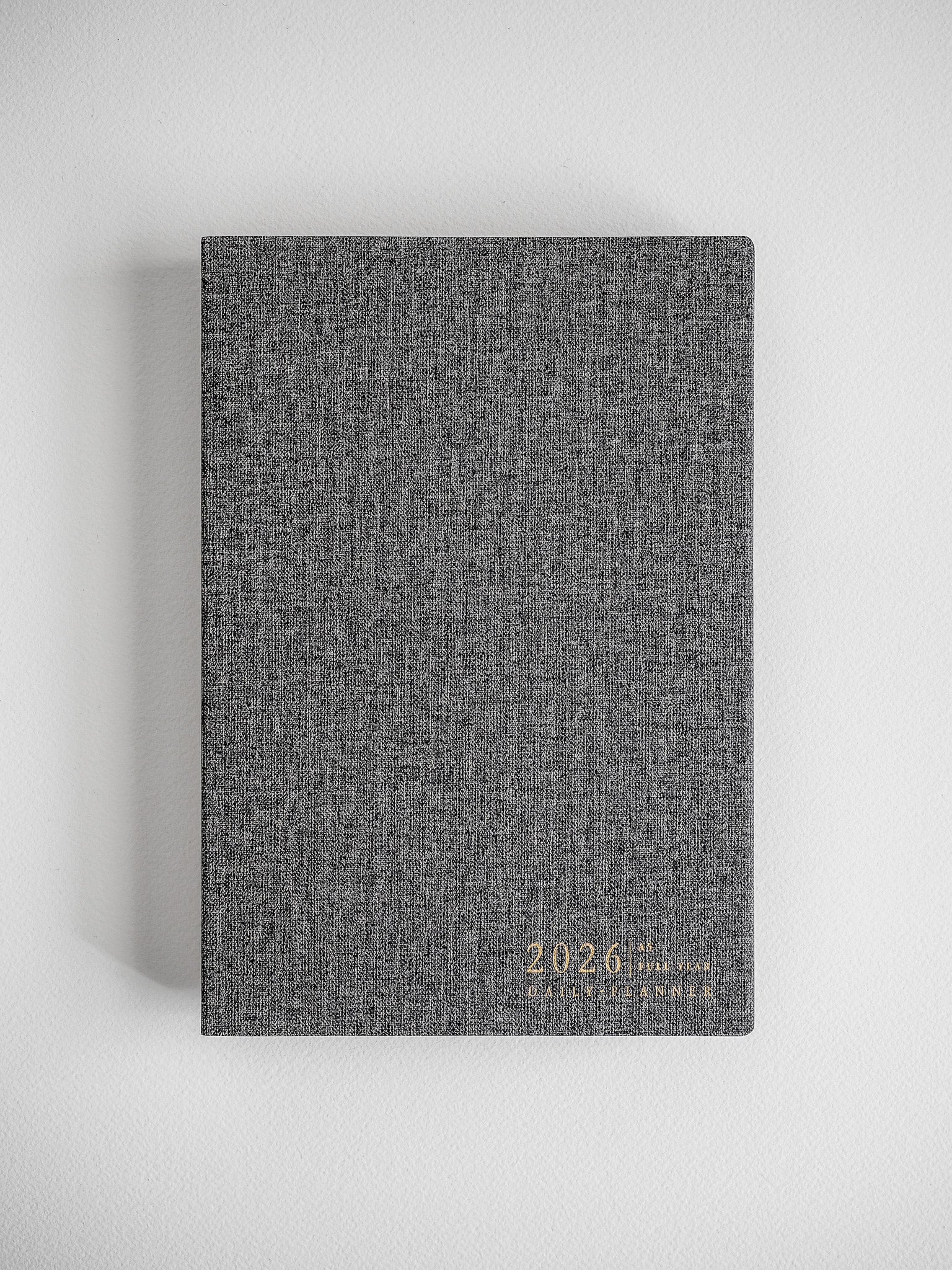 Minimalist A5 daily planner featuring a heather gray, textured cover and discreetly embossed text reading "2026 Daily Planner."