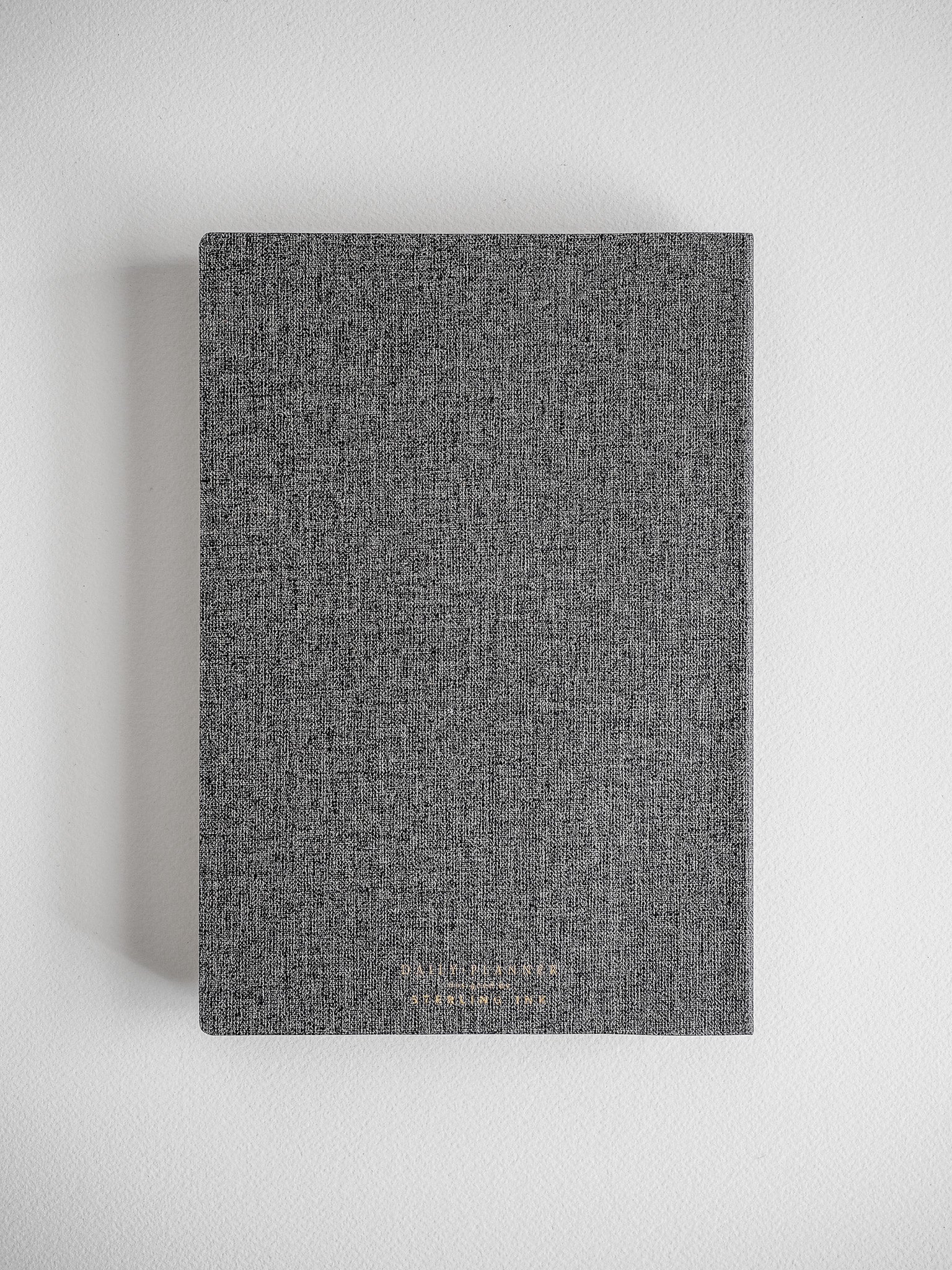 Textured A5 daily planner with a solid, dark charcoal gray cover, perfect for minimalist note-taking and organization.