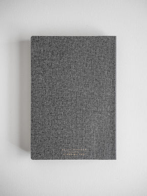 Textured A5 daily planner with a solid, dark charcoal gray cover, perfect for minimalist note-taking and organization.