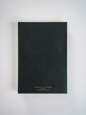 Deep charcoal A5 planner featuring a sophisticated, minimalist design and centered branding text: "COMMON PLANNER designed by STERLING INK."