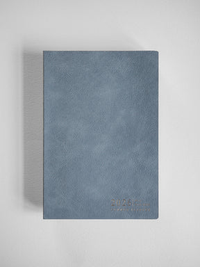 A textured, vertical A5 planner cover in slate blue, featuring a simple embossed design with the '2026 Common Planner' text.
