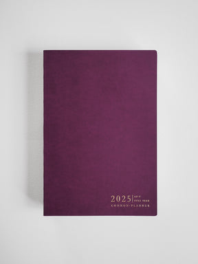 A rich, deep plum A5 vertical planner cover adorned with classic typography featuring "2025" and the name "Common Planner."