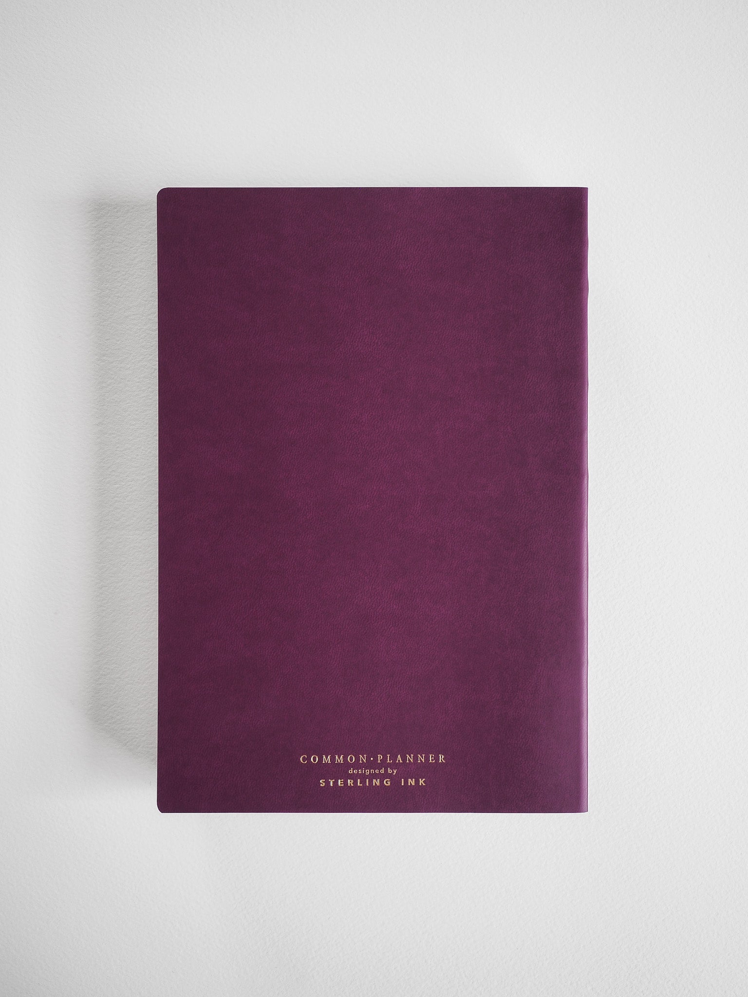 Deep plum, A5 vertical planner with a matte finish and minimalist white typography featuring the brand name "Common Planner" and "SYERLING INK."