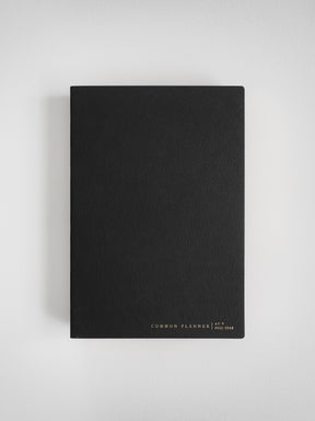 A minimalist, solid black A5 vertical planner featuring subtle white text branding that reads "COMMON PLANNER | A5 VERTICAL FULL YEAR."