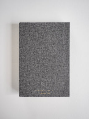 Dark gray, textured A5 vertical planner cover featuring minimalist embossed lettering for the 2026 Common Planner.