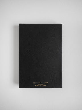 Black A5 common planner journal with faux leather binding, featuring elegant foiled text that reads "COMMON PLANNER designed by STERLING INK."