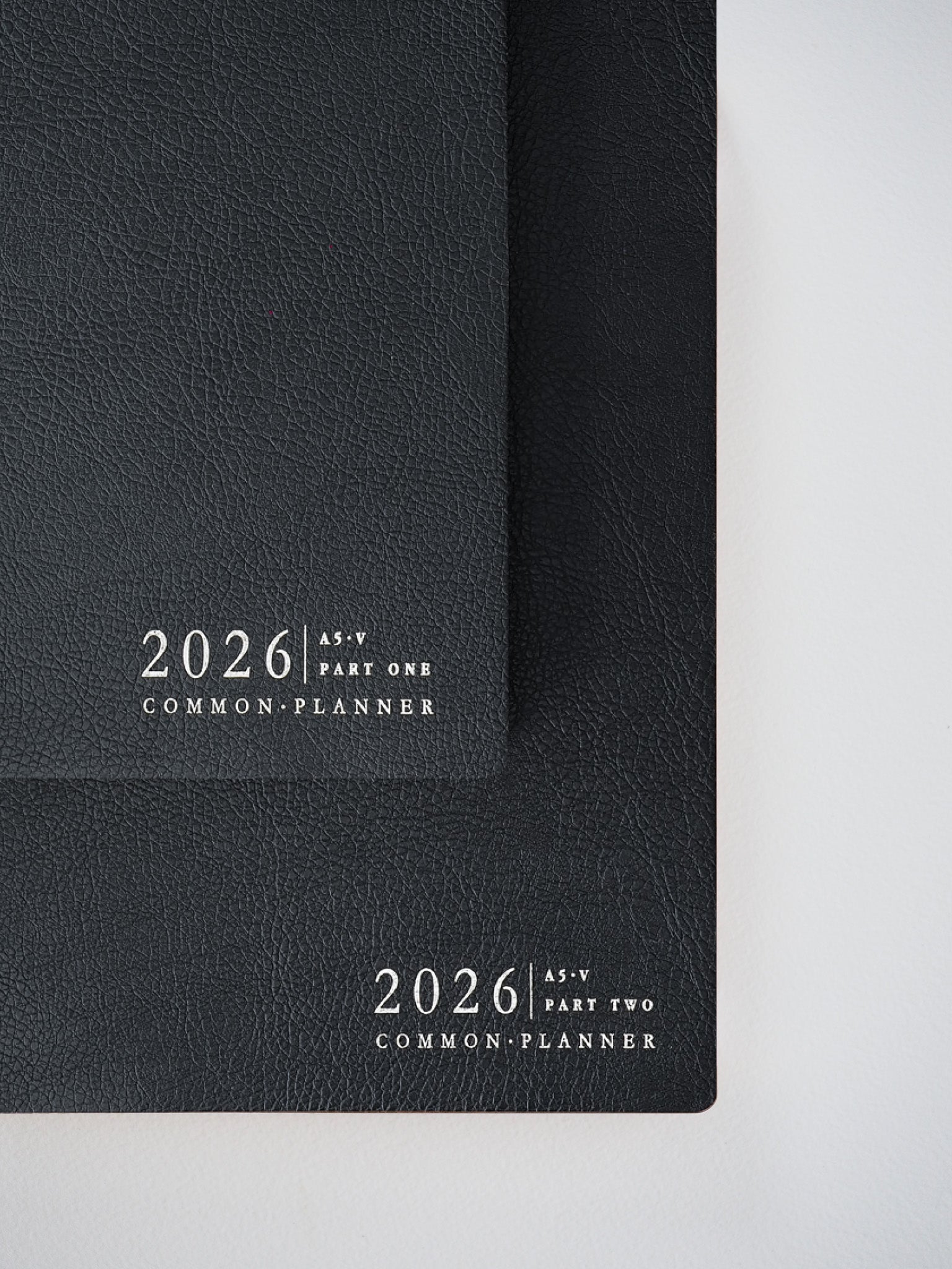 Matching set of two matte black A5 vertical planners for 2026, labeled "Part One" and "Part Two," offering a cohesive organization system.