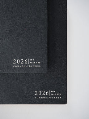 Matching set of two matte black A5 vertical planners for 2026, labeled "Part One" and "Part Two," offering a cohesive organization system.