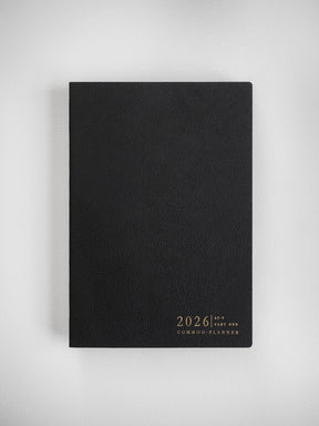 Minimalist black A5 planner with a smooth cover, featuring the centered gold-toned branding "2026 Common Planner" for organization.