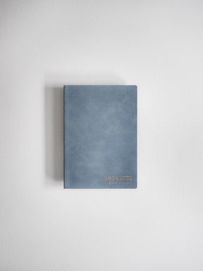 Elegant A6 horizontal planner in a muted blue-gray shade, featuring minimal metallic gold lettering that indicates the 2026 academic year.