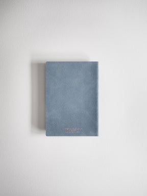 This A6 compact full-year planner features a muted blue-gray hardcover and includes minimal gold-colored branding identifying the 2026 collection on the front.