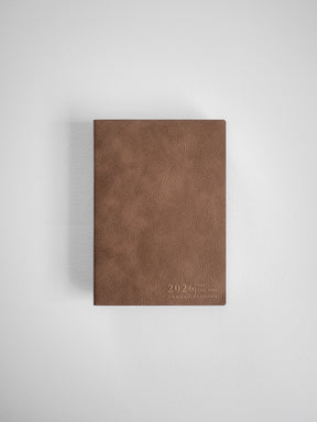 Solid A6 vertical planner cover in warm mocha brown faux leather, featuring a clean, minimalist design subtly embossed with the year 2026.