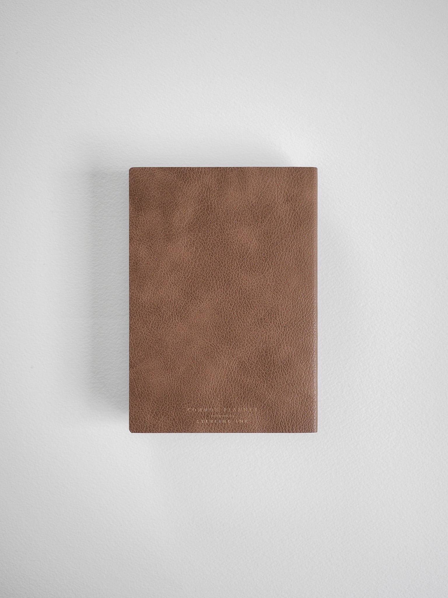 A minimalist A6 vertical planner with a textured, matte taupe brown cover, designed for full year scheduling in 2026.