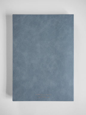 Sleek B5 compact planner featuring a solid slate blue, textured faux leather cover, perfect for organized year-long scheduling.
