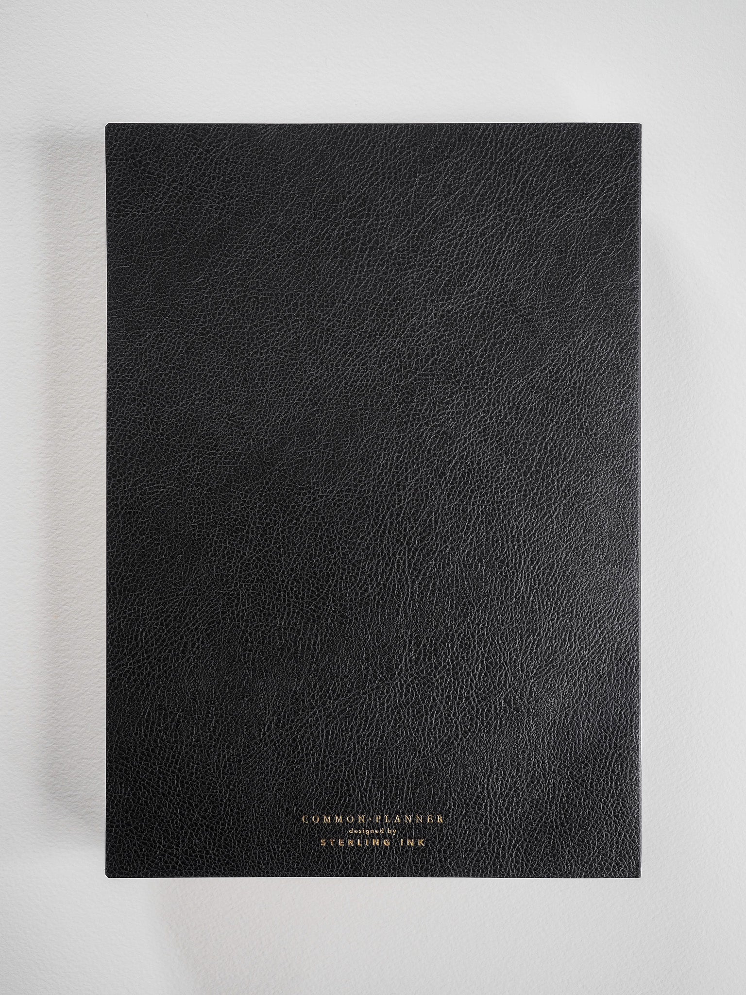 Black B5 common planner with a textured faux leather cover, featuring "Common Planner" text, designed for full-year planning.