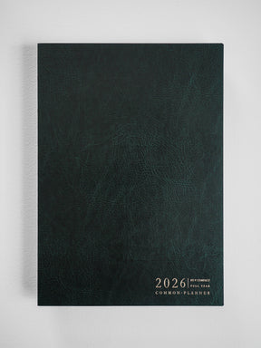 Deep slate green planner cover with a textured faux leather finish and centered gold foil debossing of the 2026 date and common planner title.