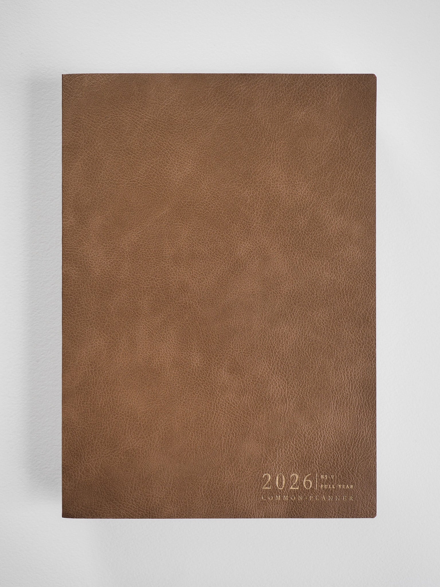 Deep brown faux leather planner cover displaying "2026" and "Common Planner" text in a clean, vertical format.