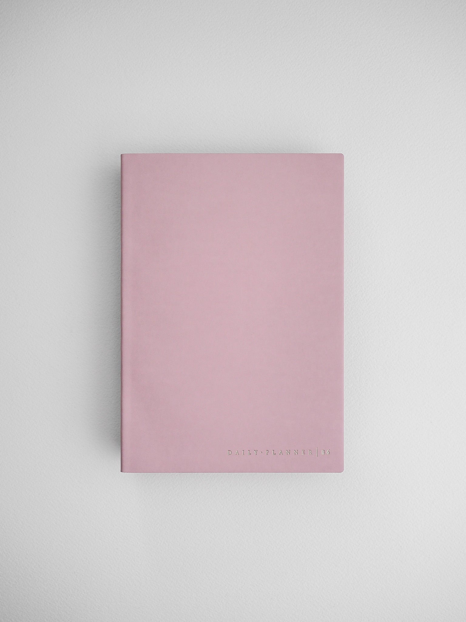Minimalist blush pink daily planner notebook featuring clean lines and "DAILY PLANNER" branding on the cover.