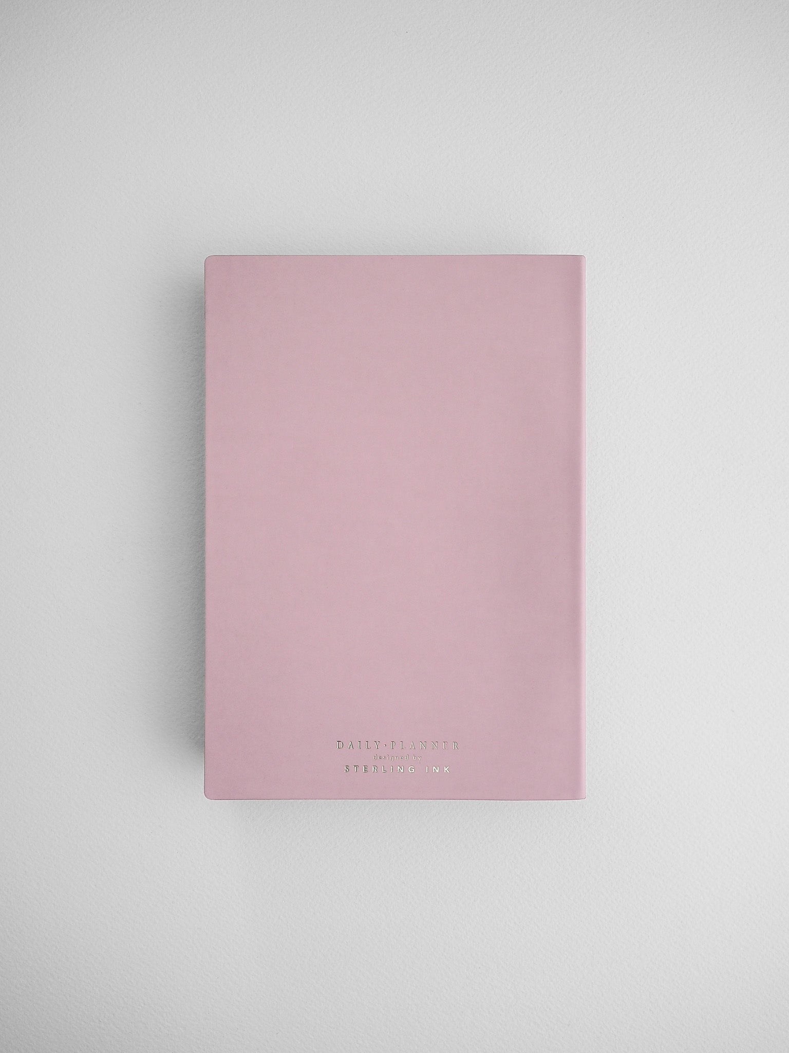 Pale pink B6 daily planner journal featuring minimalist black typography and labeled "Daily Planner" by Sterling Ink.