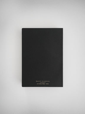 Minimalist black daily planner notebook designed for undated use, featuring elegant white branding from Sterling Ink for an organized look.