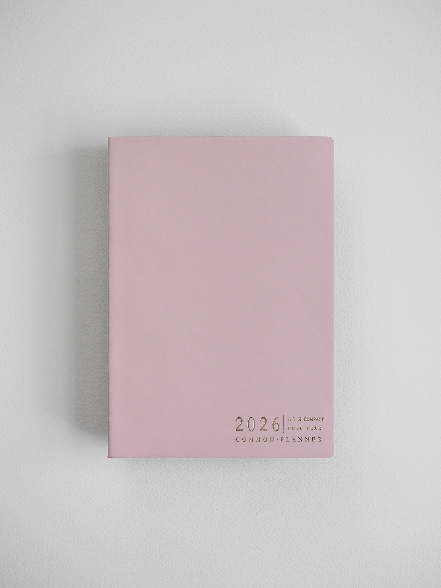 Minimalist B6 planner cover in soft pastel pink, featuring centered black typography that reads "2026 B6 Compact Full Year Common Planner."