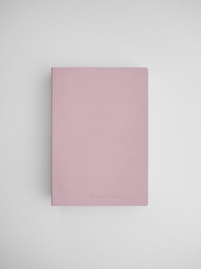 Blush pink B6 common planner notebook, featuring a minimalist design and subtle printed text for journaling or organization.