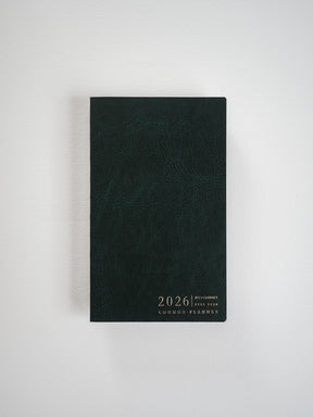 Sleek, dark slate B6 planner featuring a slim, compact vertical design with minimalist white lettering that reads "2026 Common Planner" centered on the front cover.