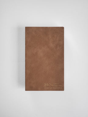 A slim, full-year 2026 planner featuring a matte, rich tan cover with "Common Planner" embossed text near the bottom.